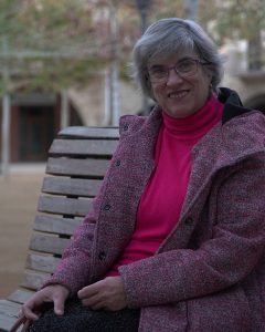 Una mujer autista sentada en un banco sonriendo mirando a cámara