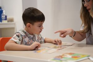Niño en una mesa leyendo unas fichas con una chica enfrente