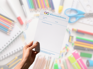 Una mano sujeta un papel sobre un fondo de lápices de colores